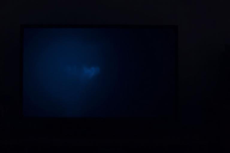 Very dim television screen in a dark room indicating a backlight fault